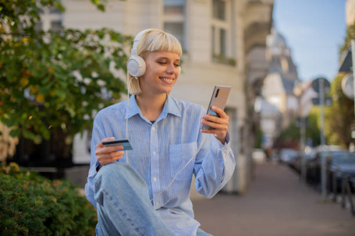 Person using a smartphone and holding a credit card, illustrating the convenience of cross-platform apps.