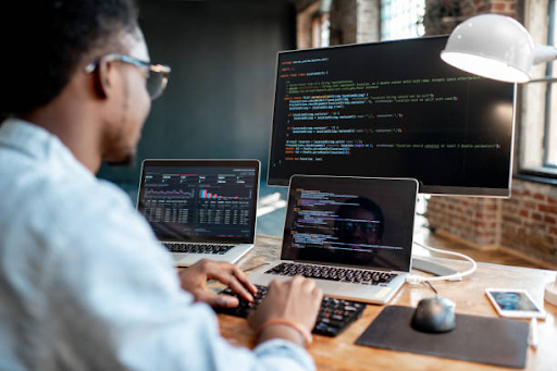 A developer codes on multiple screens, highlighting the efficiency of cross-platform app development.