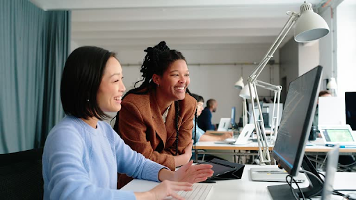 Two developers collaborating on a computer, illustrating teamwork in cross-platform app development.